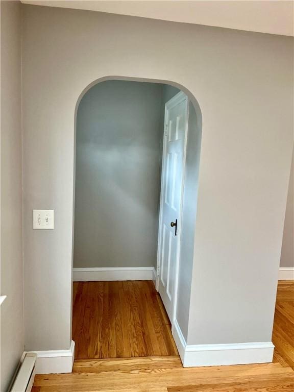 74 Leslie St, Cranston, RI 02910 - hallway with a baseboard radiator, light wood finished floors, and arched walkways
