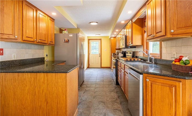1846 E Wallum Lake Rd, Burrillville, RI 02859 - kitchen featuring appliances with stainless steel finishes, brown cabinets, decorative backsplash, dark stone countertops, and recessed lighting
