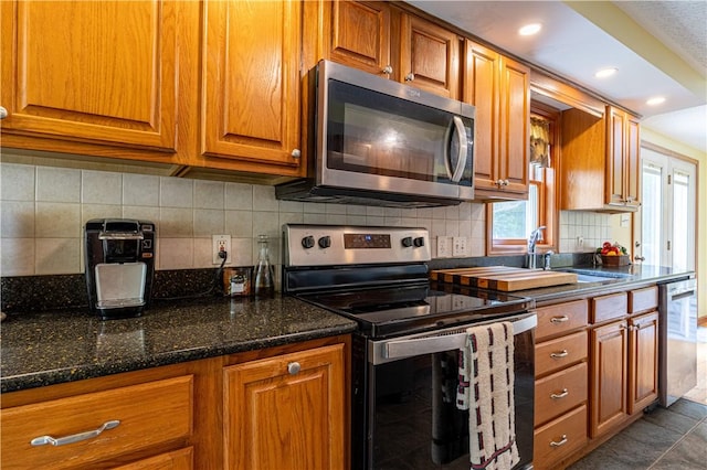 1846 E Wallum Lake Rd, Burrillville, RI 02859 - kitchen with appliances with stainless steel finishes, brown cabinets, tasteful backsplash, dark stone counters, and recessed lighting