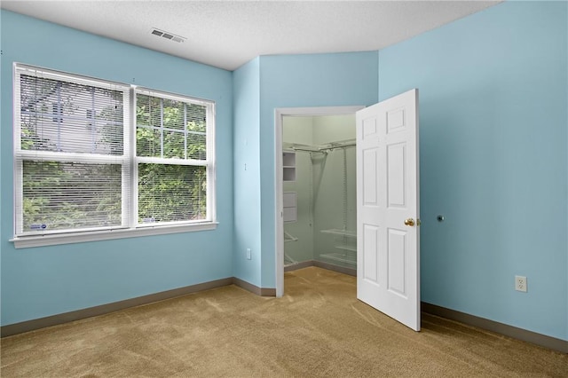 120 Mill St Unit 103, Woonsocket, RI 02895 - unfurnished bedroom with light colored carpet, a walk in closet, and a textured ceiling
