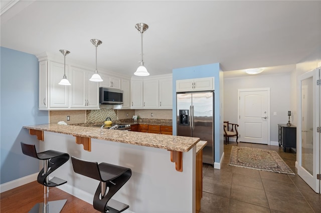 333 Atwells Ave Unit 302, Providence, RI 02903 - kitchen with stainless steel appliances, a peninsula, decorative backsplash, white cabinets, and a breakfast bar
