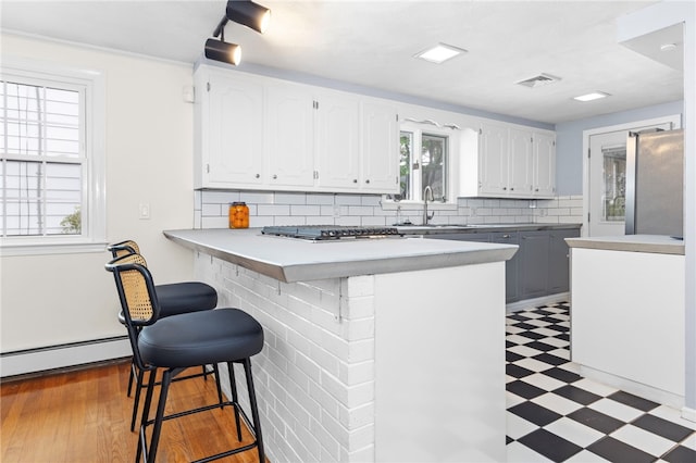 112 Edgewood Blvd, Providence, RI 02905 - kitchen featuring baseboard heating, light floors, a kitchen breakfast bar, white cabinetry, and tasteful backsplash