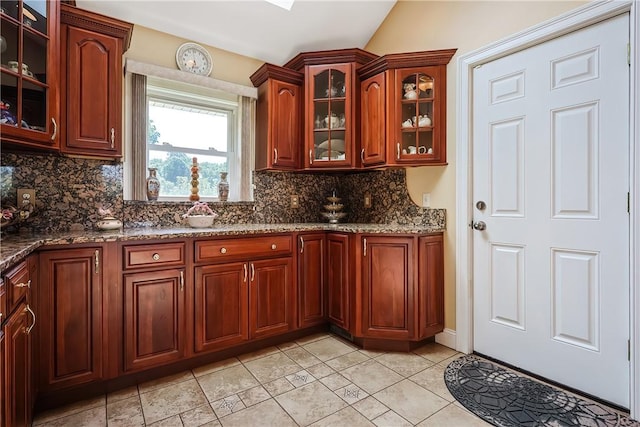240 Smith St, Attleboro, MA 02703 - kitchen with tasteful backsplash, dark stone countertops, glass insert cabinets, light tile patterned floors, and lofted ceiling
