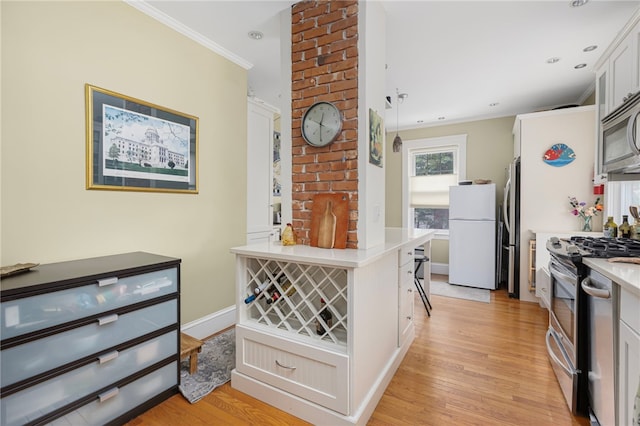 179 Cole Ave Unit 2, Providence, RI 02906 - kitchen featuring appliances with stainless steel finishes, ornamental molding, light countertops, light wood-type flooring, and white cabinets