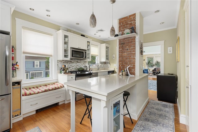 179 Cole Ave Unit 2, Providence, RI 02906 - kitchen with appliances with stainless steel finishes, a kitchen bar, crown molding, healthy amount of natural light, and tasteful backsplash