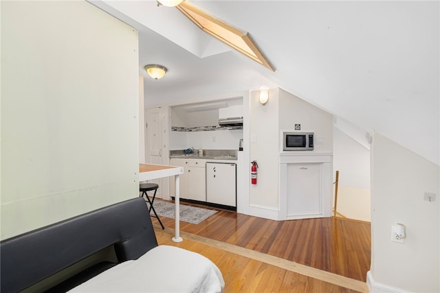179 Cole Ave Unit 2, Providence, RI 02906 - kitchen with stainless steel microwave, light wood-style flooring, vaulted ceiling, white cabinets, and white dishwasher