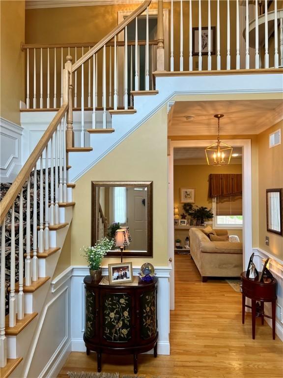 35 E Lantern Rd, Smithfield, RI 02917 - staircase with a wainscoted wall, wood finished floors, a decorative wall, a high ceiling, and a chandelier