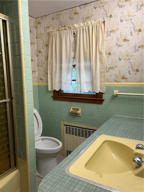 12 Oakland Ave, Johnston, RI 02919 - bathroom featuring radiator heating unit, tile walls, wallpapered walls, and wainscoting