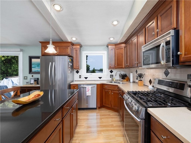 184 Vallette St, Cranston, RI 02920 - kitchen with appliances with stainless steel finishes, light wood finished floors, backsplash, decorative light fixtures, and brown cabinetry