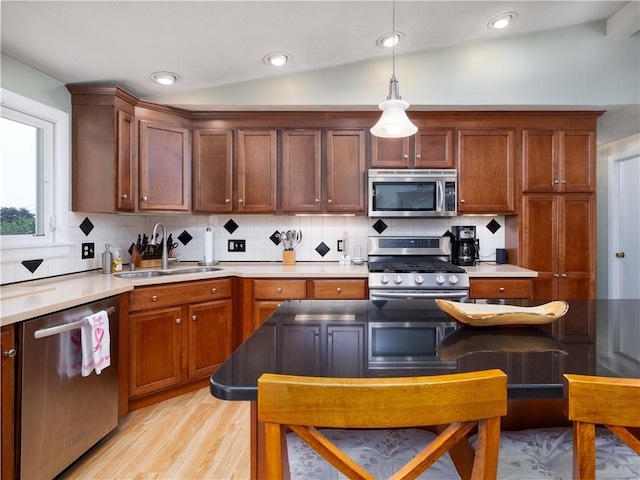 184 Vallette St, Cranston, RI 02920 - kitchen with appliances with stainless steel finishes, light wood finished floors, backsplash, hanging light fixtures, and vaulted ceiling