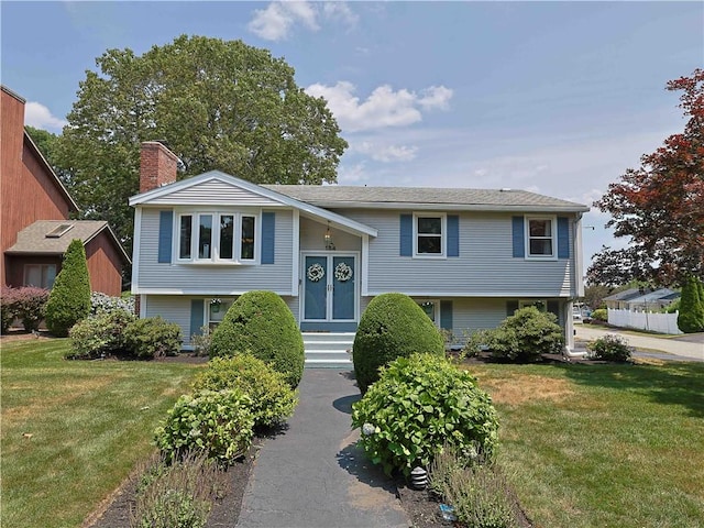 184 Vallette St, Cranston, RI 02920 - raised ranch featuring a front yard, entry steps, and a chimney