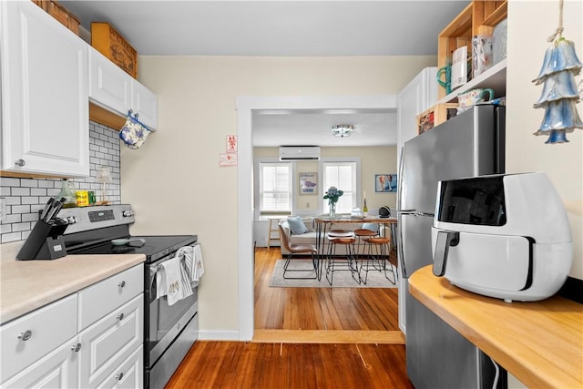 13 Dean Ave, Newport, RI 02840 - kitchen with stainless steel electric range, a wall mounted AC, dark wood finished floors, backsplash, and white cabinetry