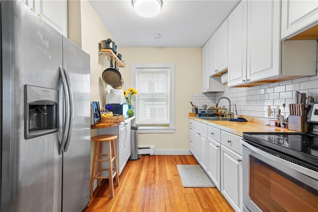 13 Dean Ave, Newport, RI 02840 - kitchen featuring appliances with stainless steel finishes, white cabinetry, decorative backsplash, light wood-type flooring, and a baseboard radiator