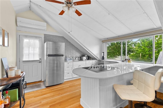 13 Dean Ave, Newport, RI 02840 - kitchen with freestanding refrigerator, an AC wall unit, vaulted ceiling, light wood finished floors, and white cabinetry