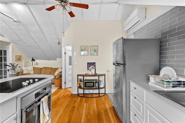 13 Dean Ave, Newport, RI 02840 - kitchen featuring stainless steel appliances, a wall mounted air conditioner, light wood-style flooring, ceiling fan, and white cabinets
