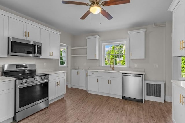 11 Taft St, Coventry, RI 02816 - kitchen with appliances with stainless steel finishes, open shelves, light countertops, white cabinets, and light wood-style floors