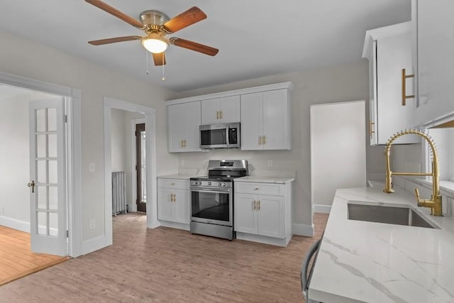 11 Taft St, Coventry, RI 02816 - kitchen featuring stainless steel appliances, light wood-type flooring, ceiling fan, and light stone countertops