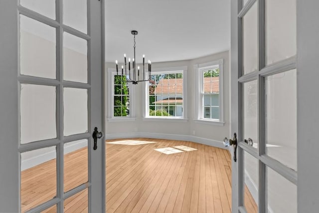 11 Taft St, Coventry, RI 02816 - unfurnished dining area with light wood-style flooring, a chandelier, and french doors