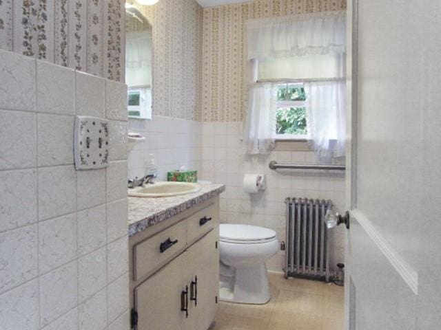 21 Hemlock Ave, Cranston, RI 02910 - bathroom with radiator, wallpapered walls, vanity, tile walls, and a wainscoted wall