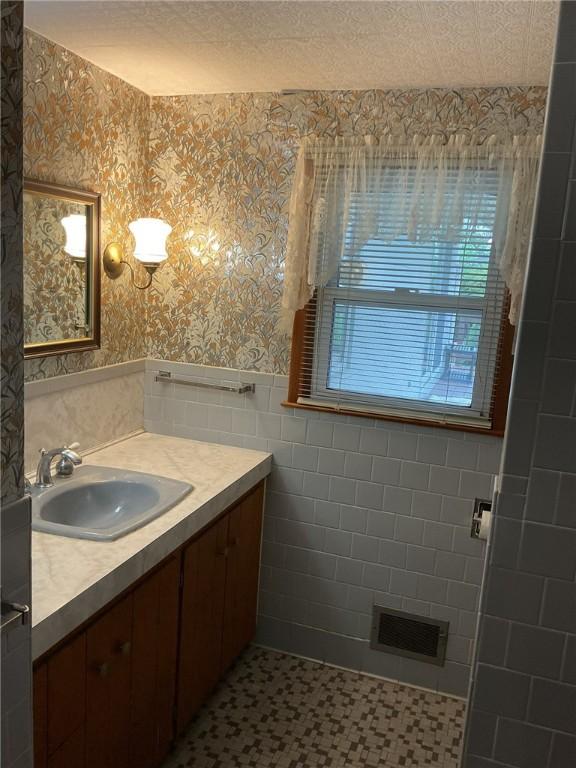 19 Leawood Dr, Cranston, RI 02920 - bathroom featuring wallpapered walls, a wainscoted wall, vanity, tile patterned floors, and tile walls