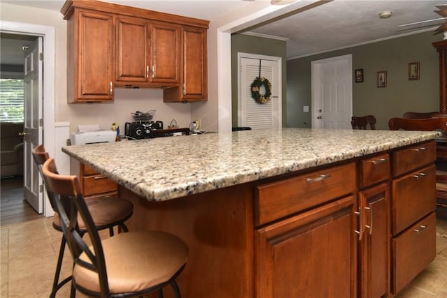 32 Harrington Dr, Johnston, RI 02919 - kitchen featuring a kitchen bar, a center island, crown molding, light stone counters, and brown cabinets