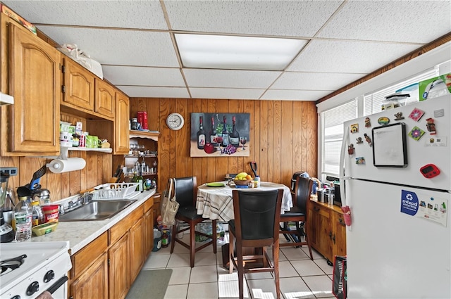 1264 Elmwood Ave, Providence, RI 02907 - kitchen featuring freestanding refrigerator, a paneled ceiling, light countertops, wooden walls, and light tile patterned floors