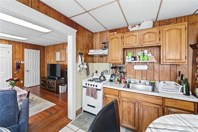1264 Elmwood Ave, Providence, RI 02907 - kitchen with wooden walls, white gas stove, light countertops, under cabinet range hood, and dark wood finished floors