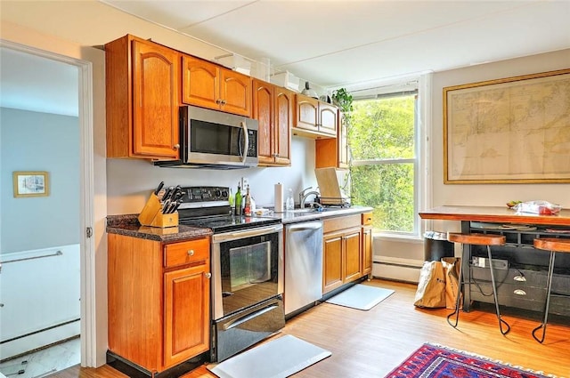 571 Spring St, Newport, RI 02840 - kitchen with stainless steel appliances, light wood-style floors, baseboard heating, and brown cabinets
