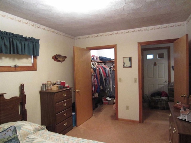 carpeted bedroom featuring a walk in closet and a closet