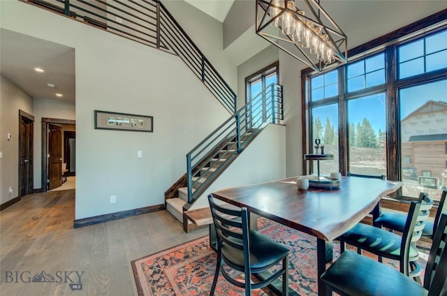 dining area with a chandelier, wood-type flooring, and a high ceiling