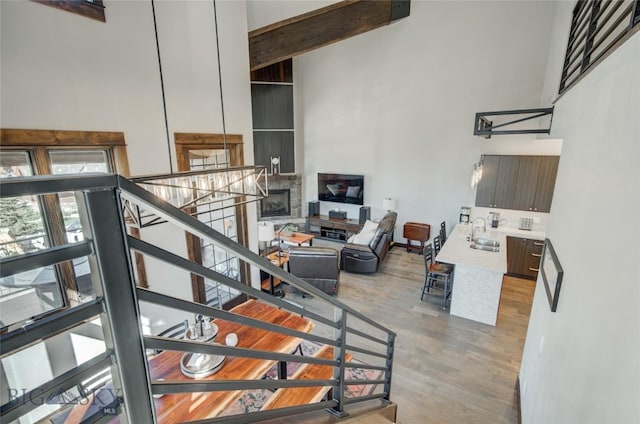 staircase with a stone fireplace, sink, a towering ceiling, and hardwood / wood-style flooring