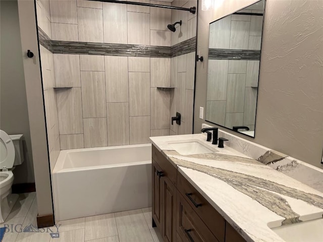 full bathroom featuring tile patterned flooring, vanity, tiled shower / bath combo, and toilet