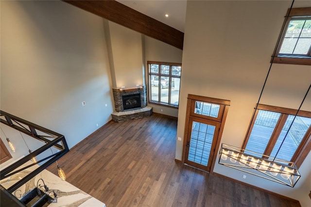 27A Heavy Runner Rd Unit 27A, Big Sky, MT 59716 - unfurnished living room featuring high vaulted ceiling, wood finished floors, a stone fireplace, stairs, and beam ceiling