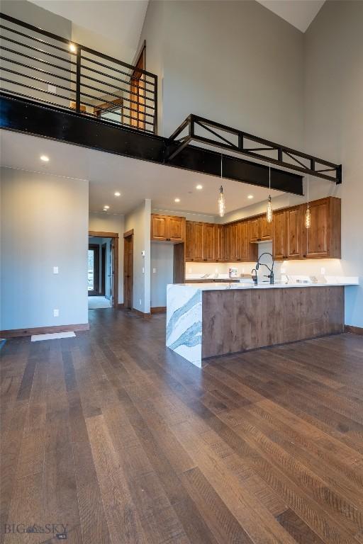 kitchen featuring kitchen peninsula, a towering ceiling, dark hardwood / wood-style floors, and hanging light fixtures