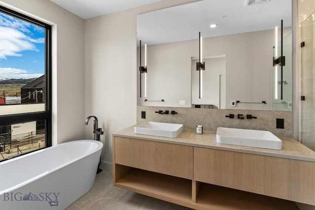 full bathroom featuring double vanity, a soaking tub, decorative backsplash, and a sink