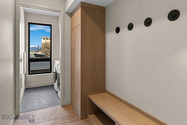 mudroom with light wood-style flooring, baseboards, and washer and clothes dryer