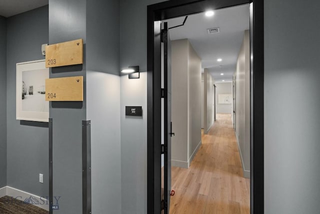 hall featuring light wood-style floors, recessed lighting, visible vents, and baseboards