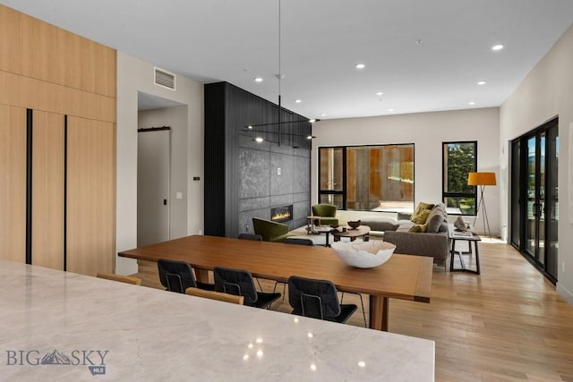 kitchen featuring light stone counters, a fireplace, visible vents, light wood finished floors, and modern cabinets