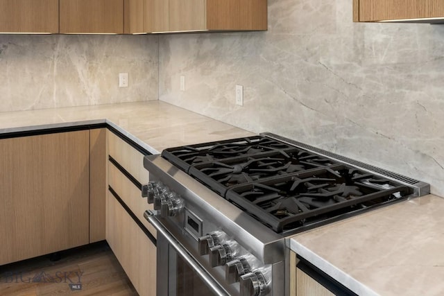 kitchen featuring light countertops, backsplash, high end stainless steel range oven, and dark wood finished floors