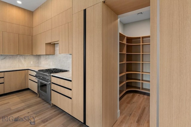 interior space featuring light brown cabinetry, light wood-style flooring, and high end range