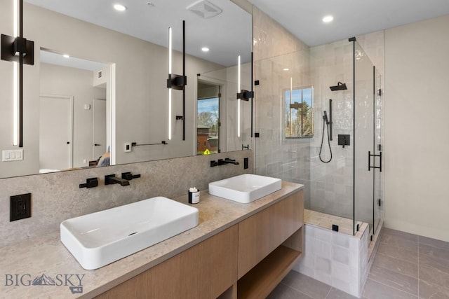 bathroom with a stall shower, a sink, backsplash, and double vanity