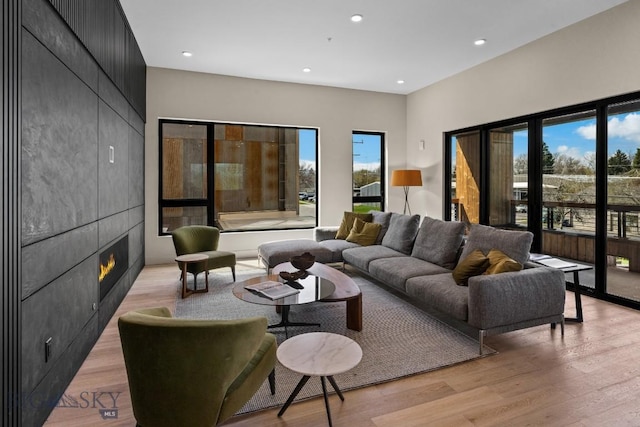 living room with light wood-type flooring, a tiled fireplace, and recessed lighting