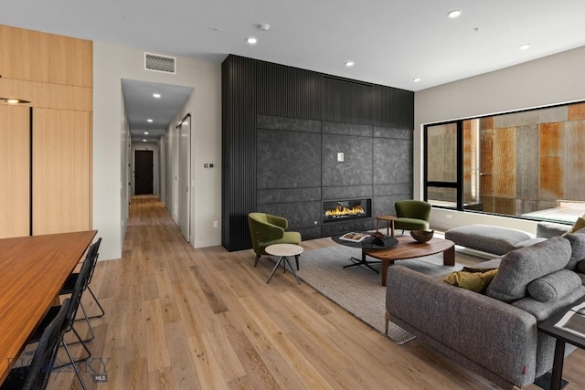 living room with recessed lighting, visible vents, a fireplace, and light wood-style flooring