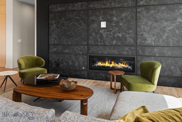 sitting room featuring a large fireplace and wood finished floors