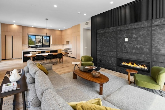 living area featuring recessed lighting, a tile fireplace, and light wood-style floors