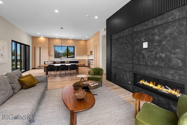 living room featuring light wood-style floors, recessed lighting, and a tiled fireplace