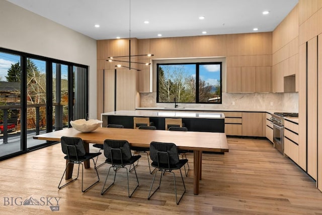 kitchen featuring stainless steel range, decorative backsplash, light wood-style flooring, modern cabinets, and light brown cabinets