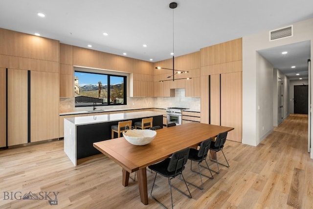 kitchen with stainless steel range, modern cabinets, a kitchen island, light countertops, and a sink