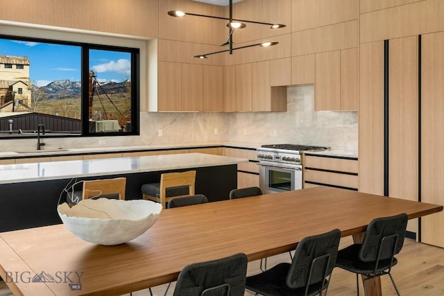 kitchen featuring a sink, light countertops, high end stove, and light brown cabinets