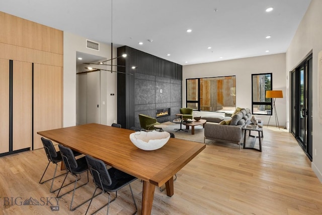 dining room featuring light wood-style floors, a tile fireplace, visible vents, and recessed lighting